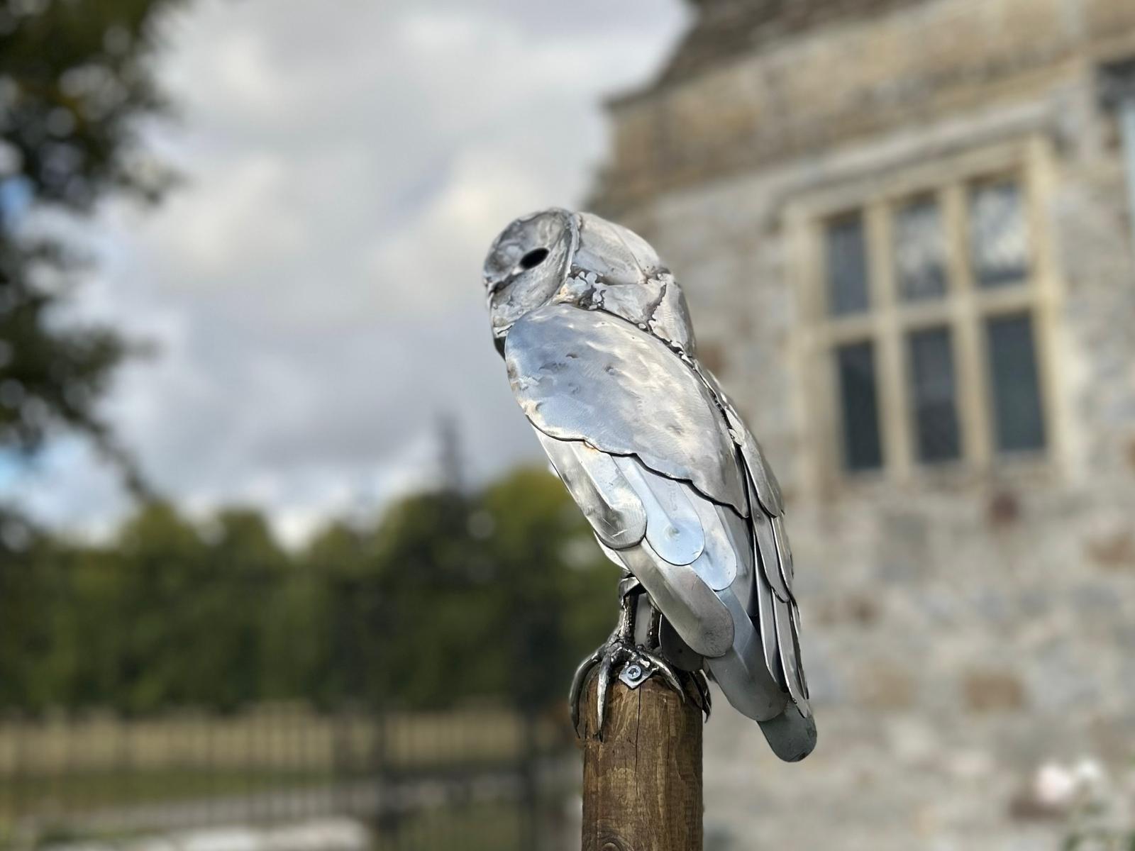 Perched barn owl sculpture in brushed steel, showing the individual hand-hammered plates and overlapping feather sheets