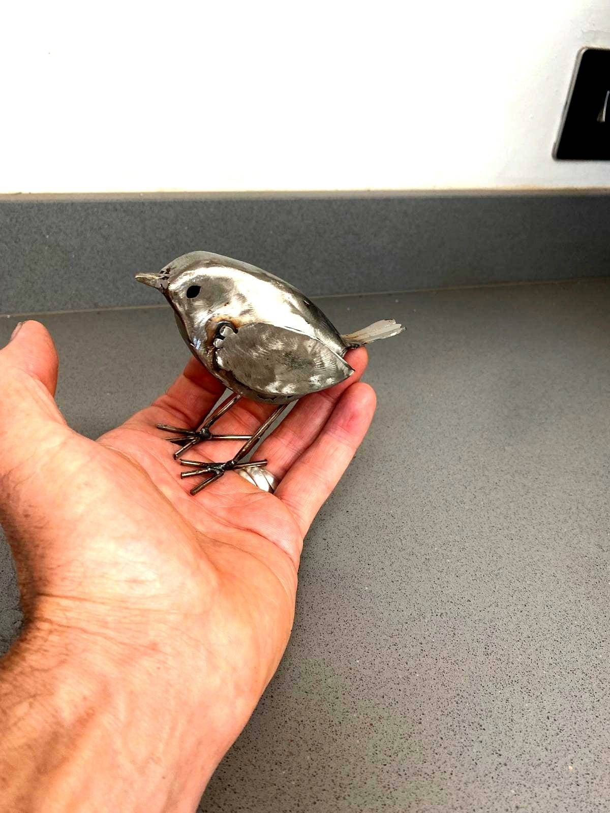 Wren metal sculpture held in craftsman's hand
